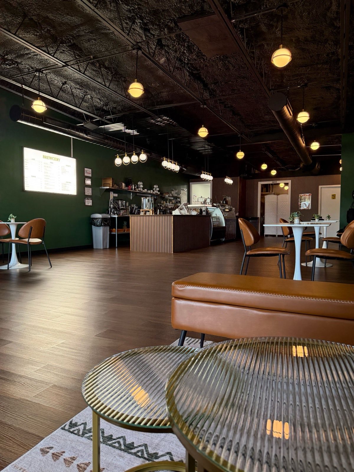 The warm, welcoming interior of Brewcery — service counter, leather banquette seating and globe lighting in Tyler, TX